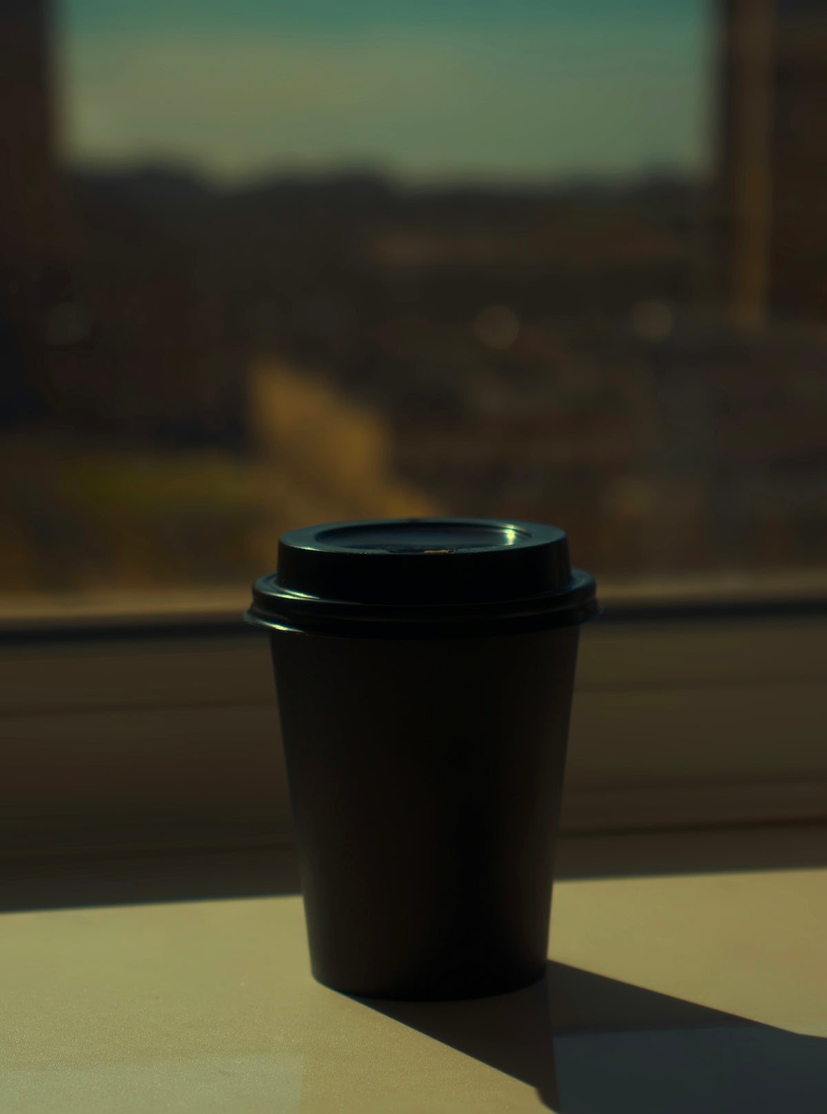 A coffee cup sits on a windowsill.