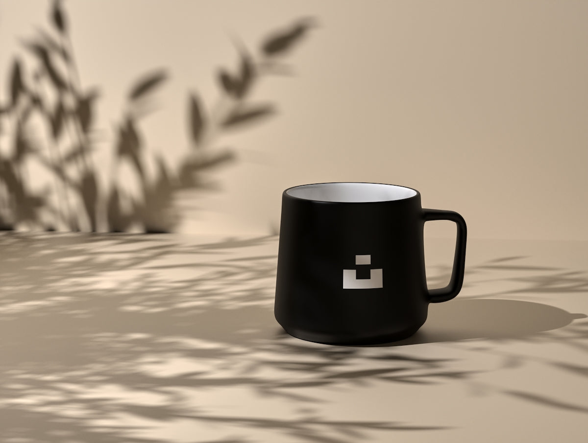 Black mug with logo against a neutral background.